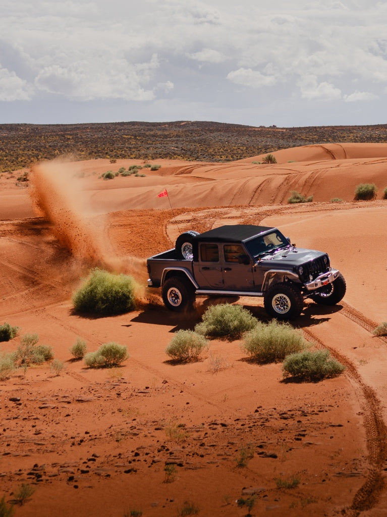 Nemesis Industries Jeep Gladiator JT off-roading through desert sand dunes with lifted suspension and oversized tires