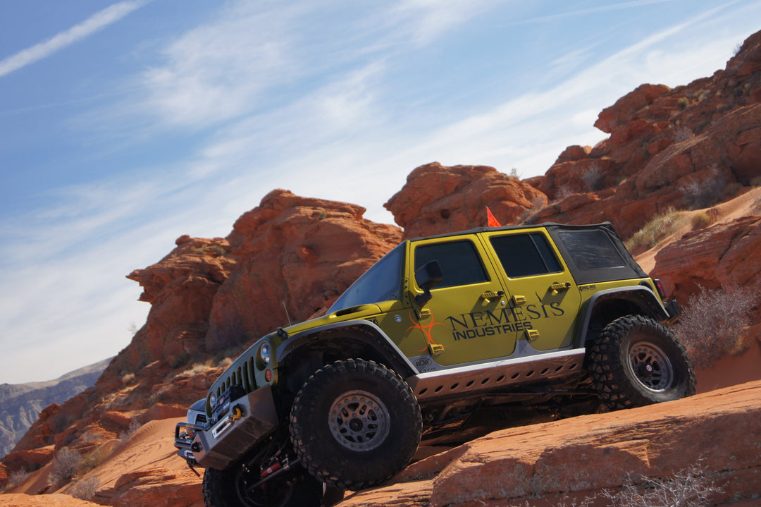 Nemesis Industries Jeep Wrangler JK Unlimited with rock sliders and fender flares climbing red sandstone