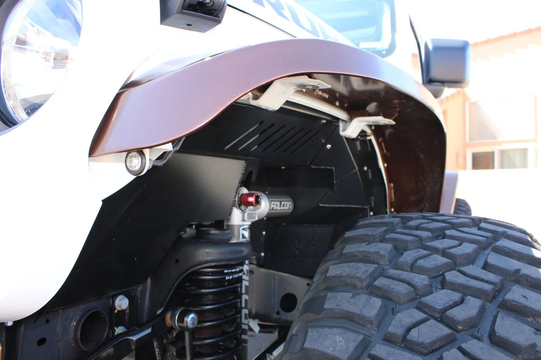 Black Nemesis front inner fender liner with vent slots around a Falcon 3.3 shock on a white Jeep.