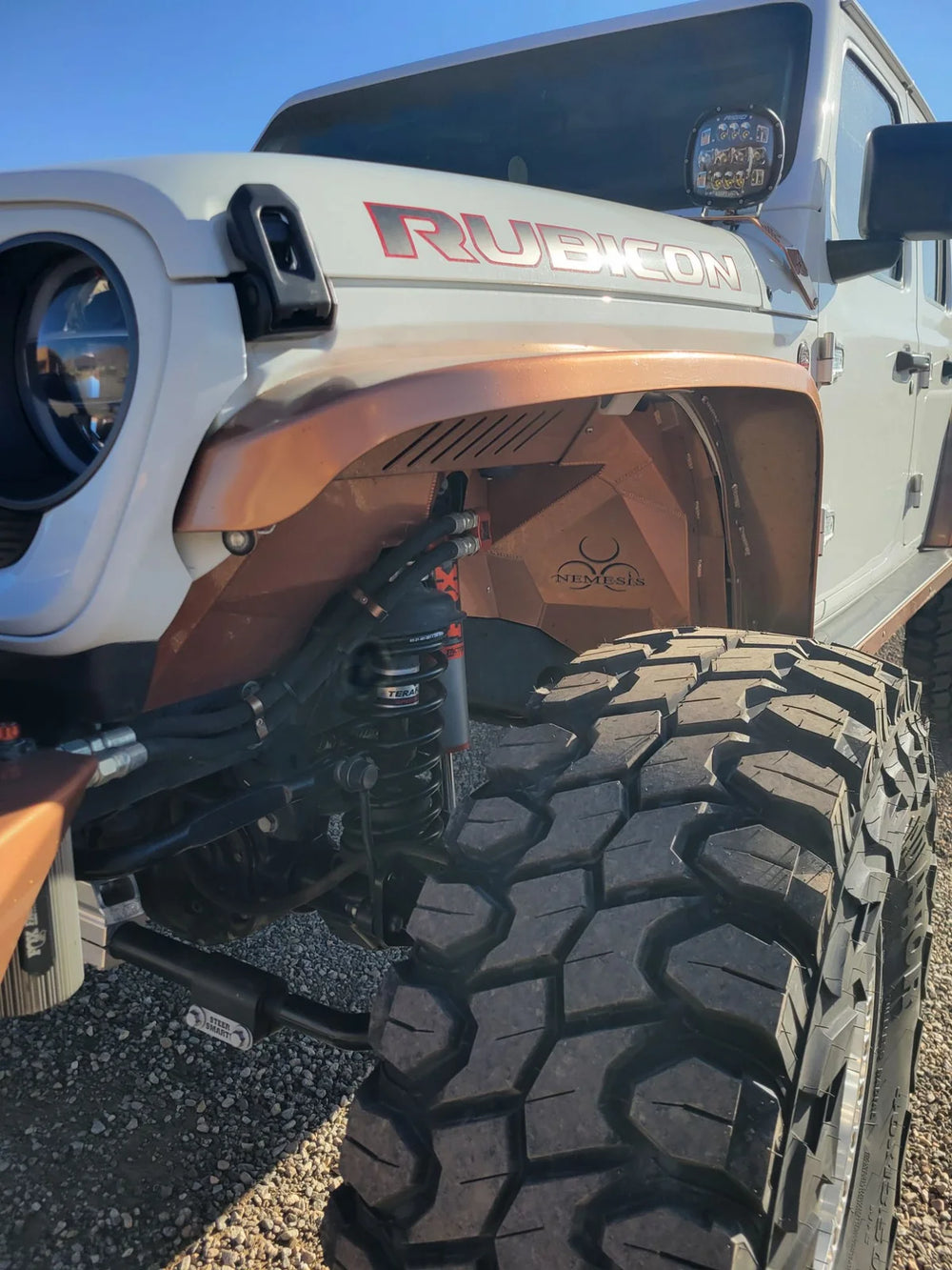Copper-colored Nemesis front inner fender liner and Fox 3.0 shocks on a white Jeep Rubicon.